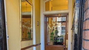 A hallway with a patterned carpet leading to a door with a glass panel. - The Sycamore Guest House (York)