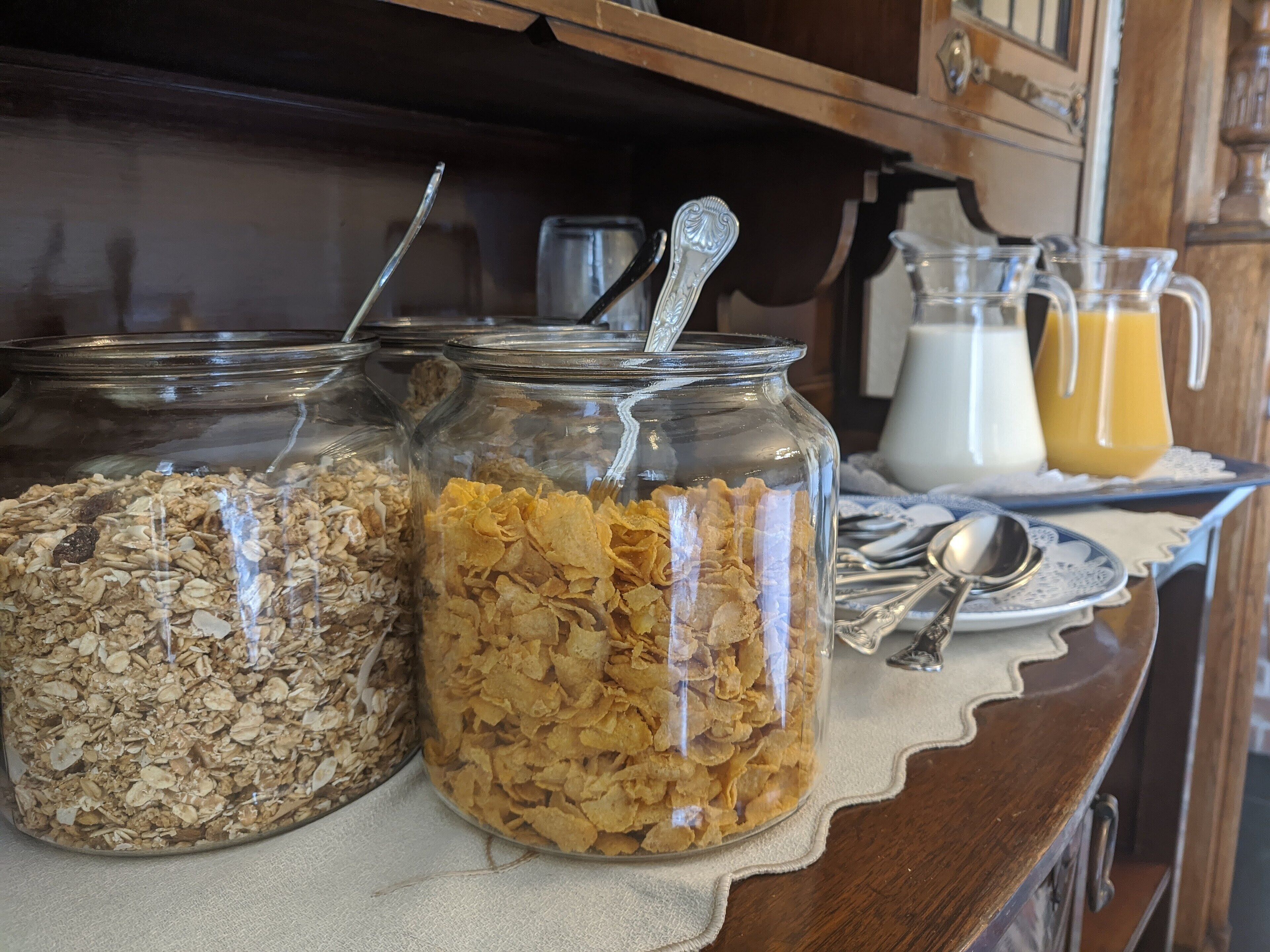 Tres frascos de vidrio con diferentes tipos de cereal sobre una mesa de madera.