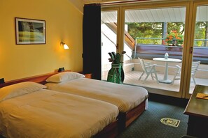 A hotel room with two beds, a balcony with a table and chairs, and a view of greenery outside. - Golf Hotel La Pinetina (Carbonate)