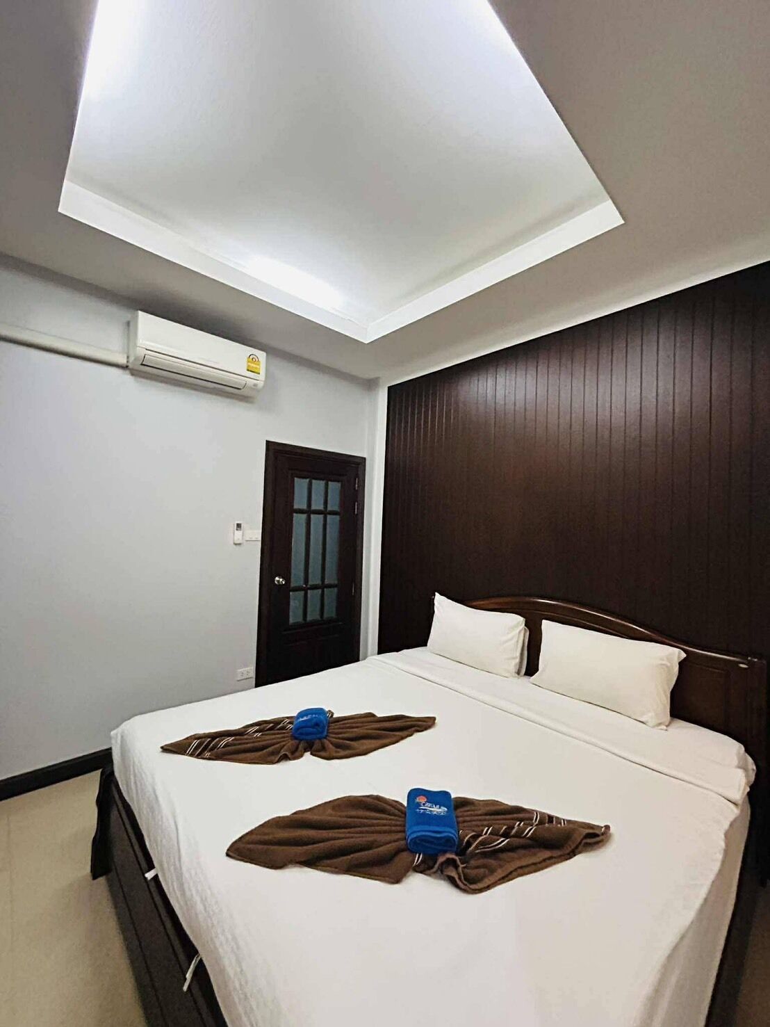 Une chambre d’hôtel équipée d’un lit, d’une porte, d’un appareil de climatisation et d’un luminaire au plafond.