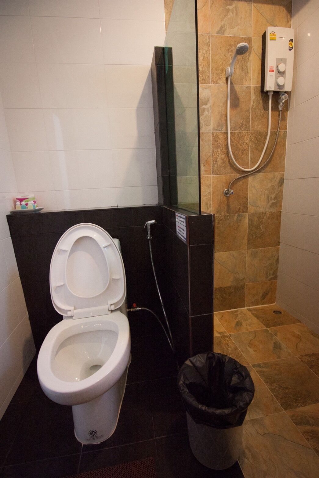 Un baño con inodoro, cabina de ducha de vidrio y calentador de agua.