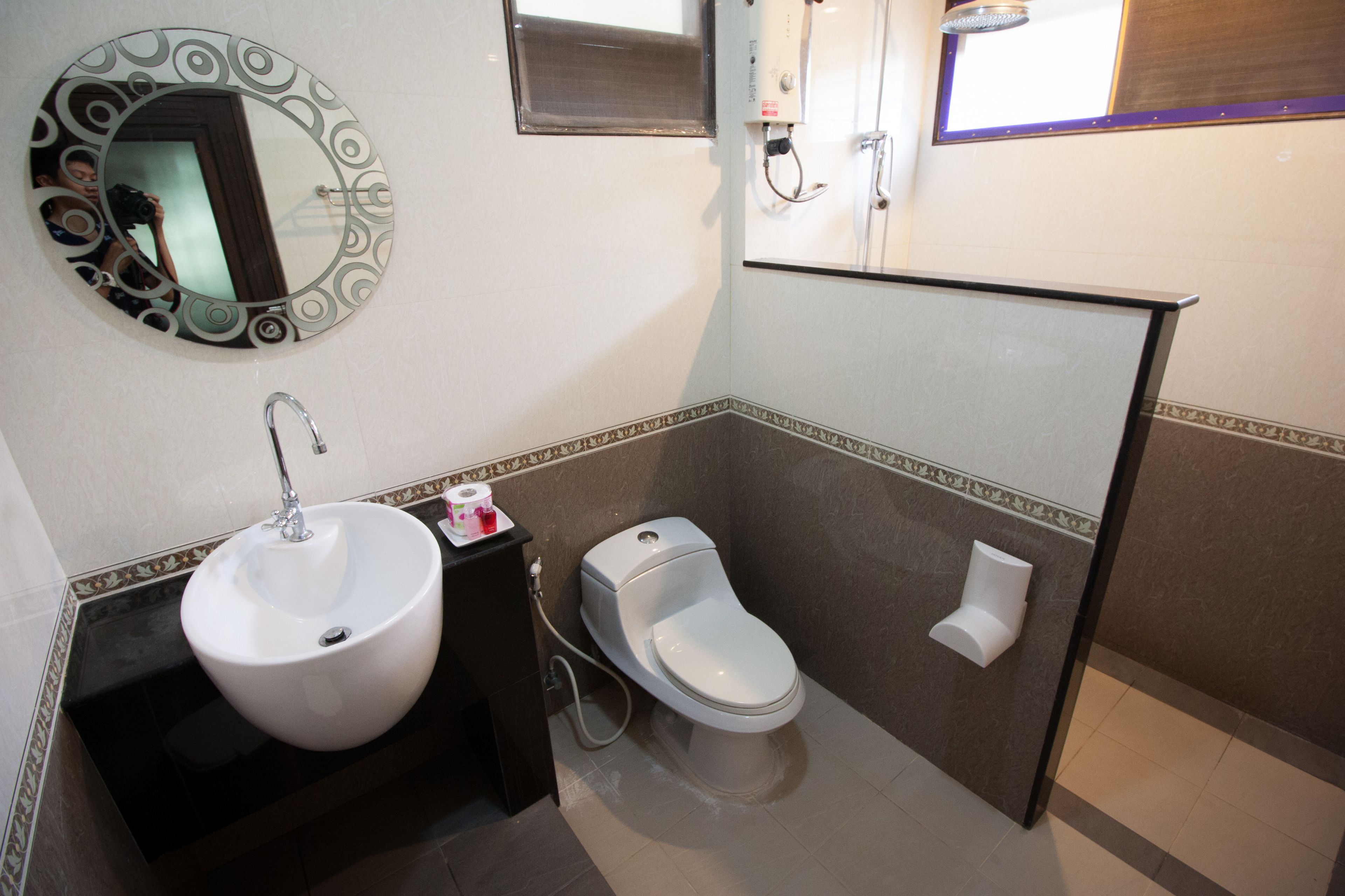 Un bagno con uno specchio rotondo, un lavandino bianco e un water.