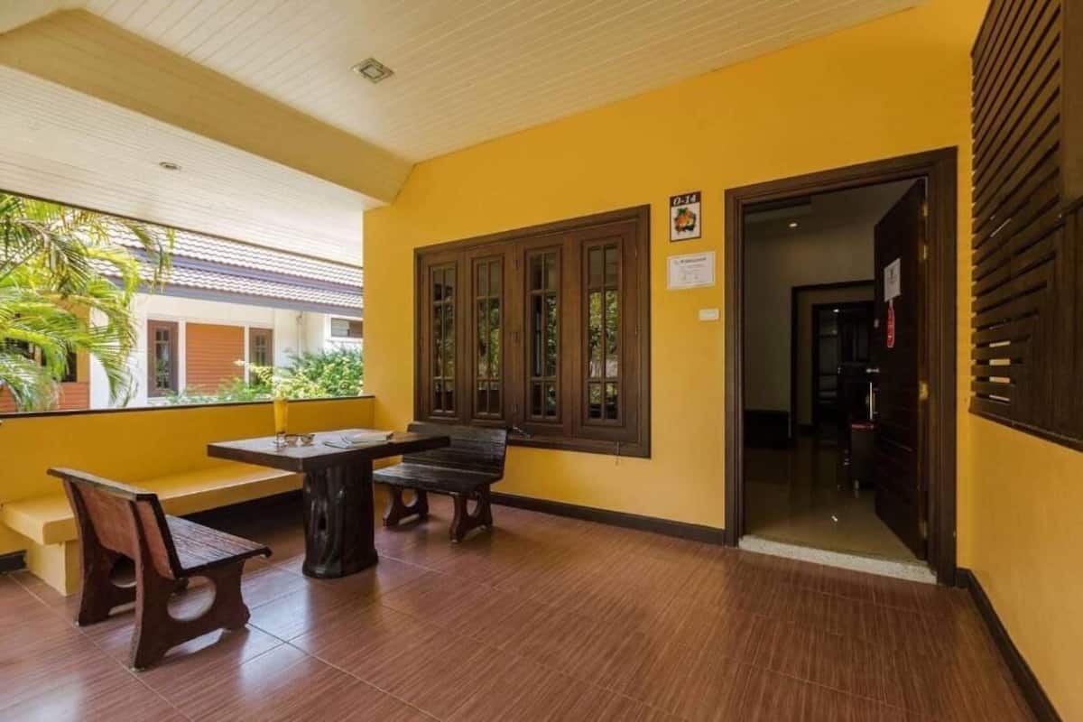 A yellow-walled room with a wooden bench, a table, and a window with wooden frames.