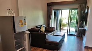 Een moderne woonkamer met een grote koelkast, een bank en een schuifdeur naar een buitenruimte.