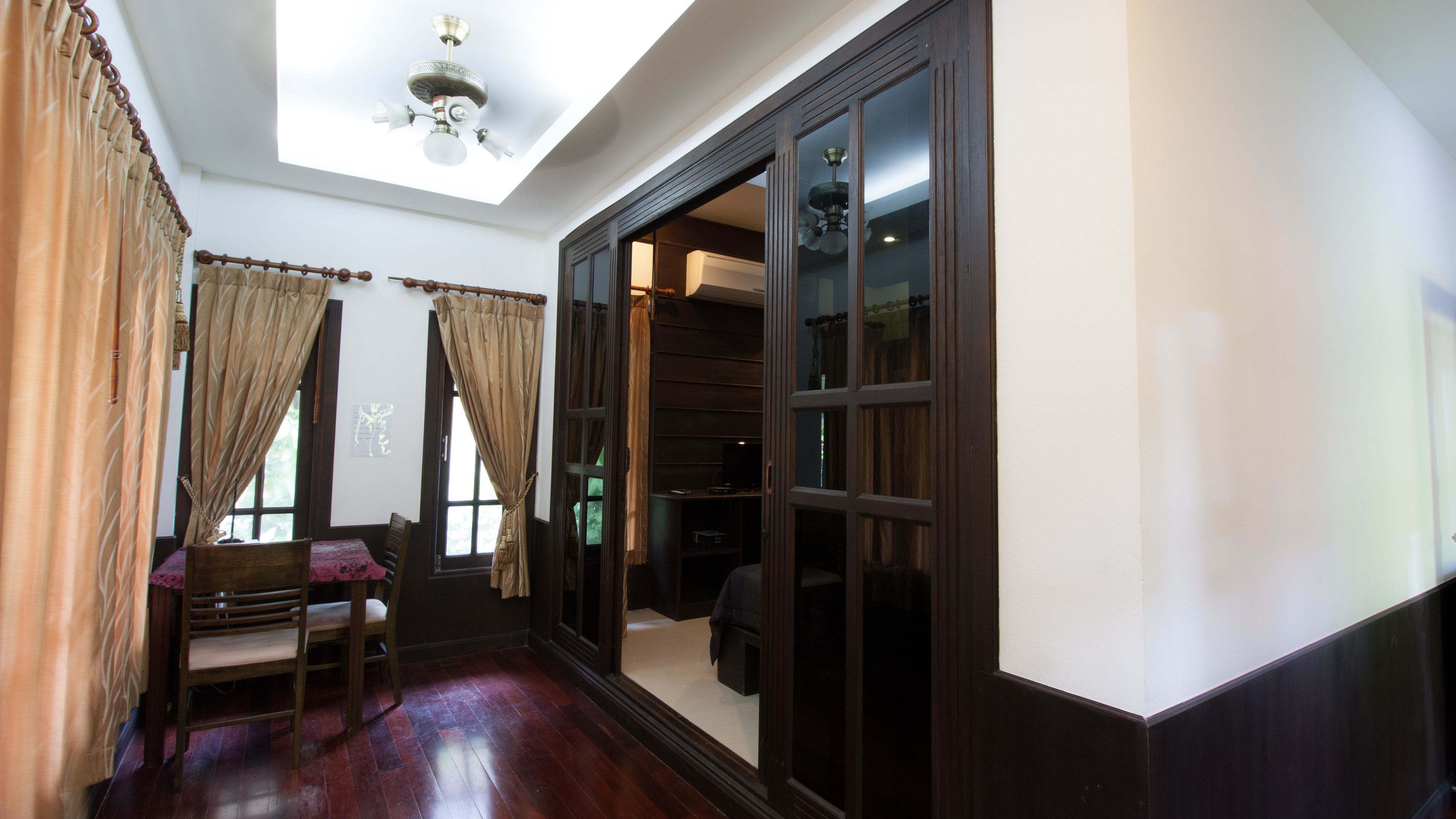 A room with a wooden floor, a ceiling fan, and a large sliding door leading to a closet.