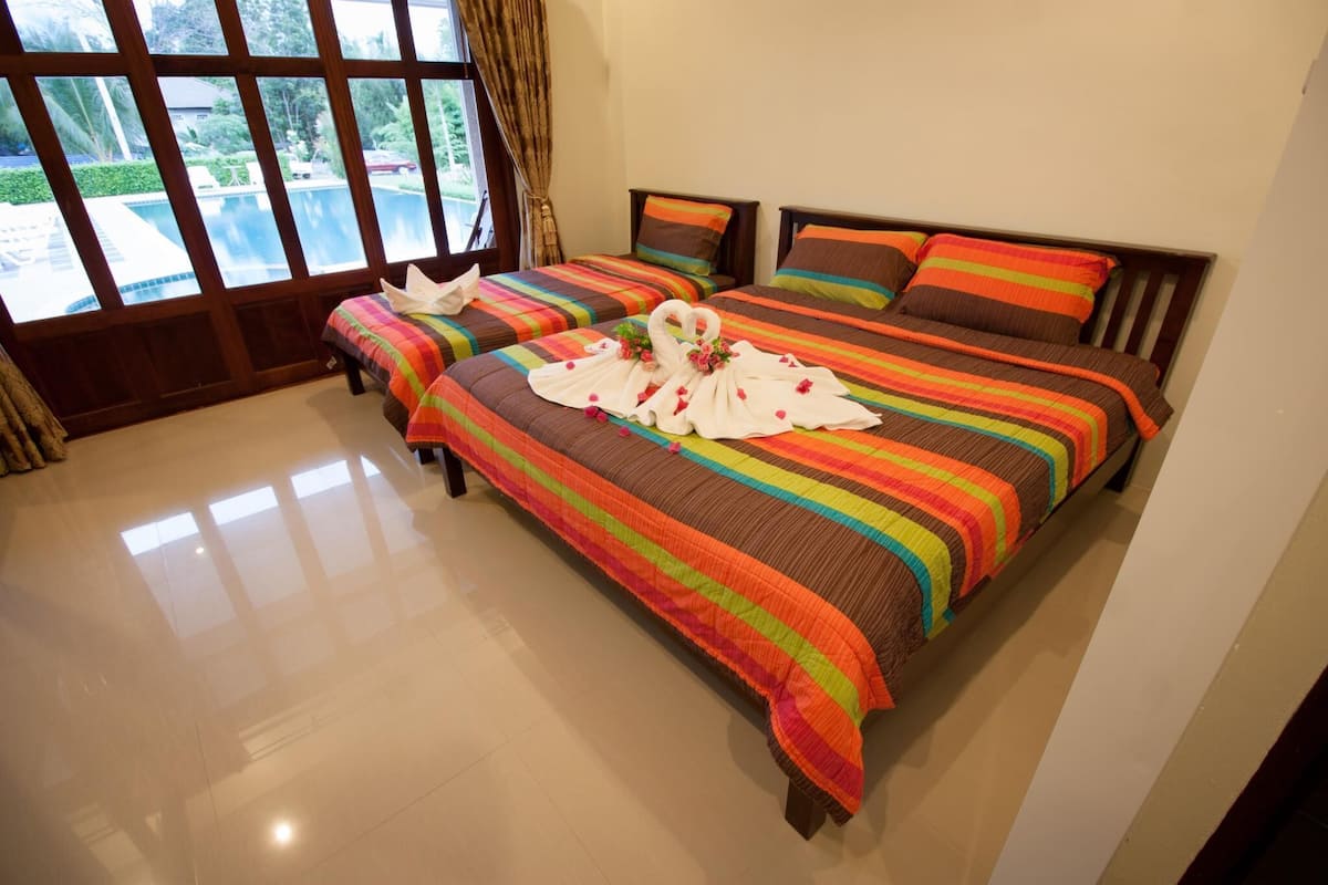A hotel room with two beds, large windows, and a view of a swimming pool.