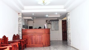 A room with a wooden reception desk, a dining area with wooden chairs, a marble floor, and a ceiling with recessed lighting. - Highfive Guest House (Pattaya)
