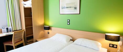 A hotel room with two beds, a desk, a chair, a wardrobe, and a painting on the wall.