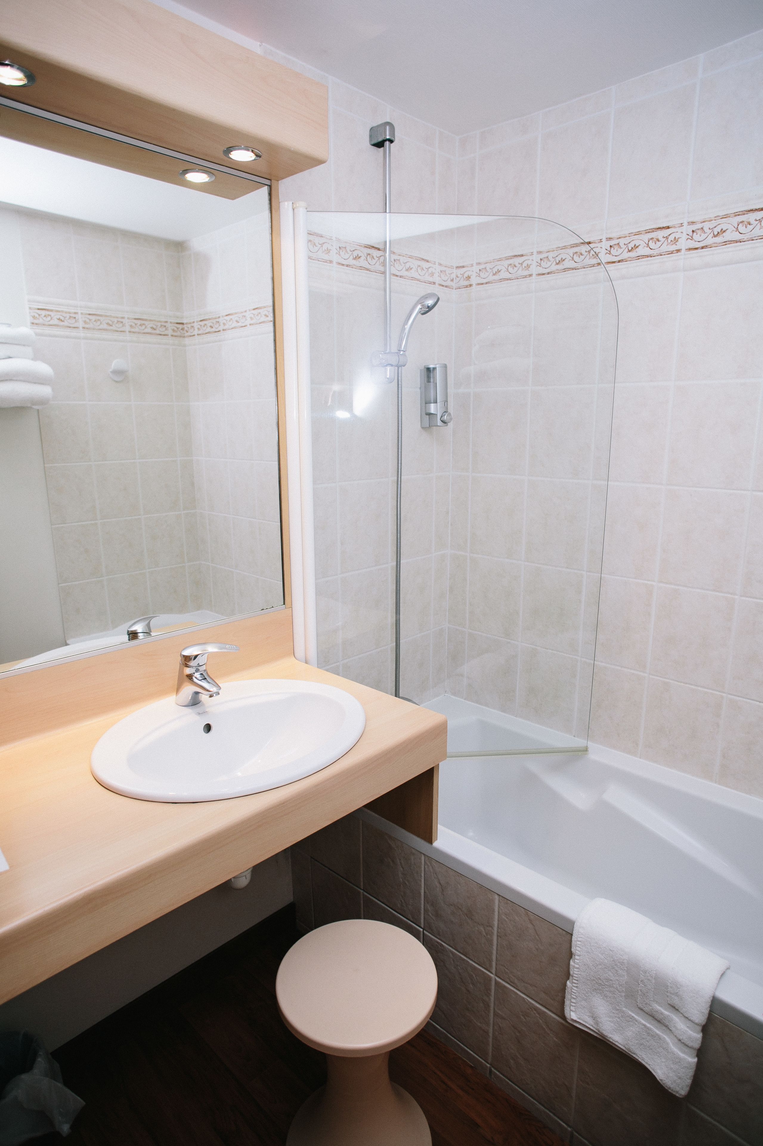 A bathroom with a sink, mirror, toilet, and shower.
