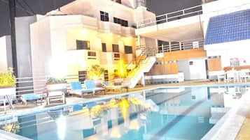 Una piscina al aire libre, sillones reclinables de piscina