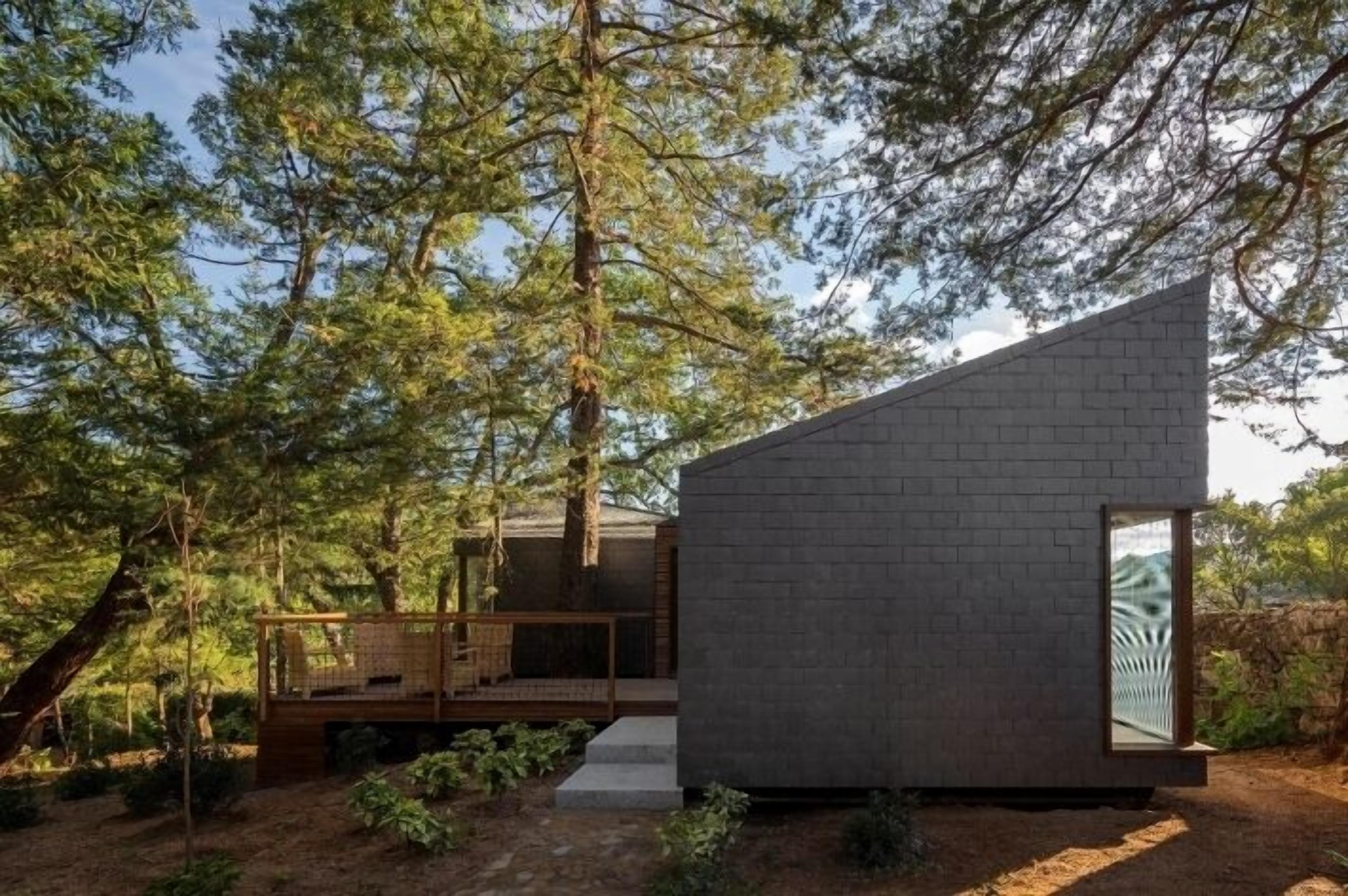 Una cabaña moderna y minimalista con techo inclinado, rodeada de un bosque denso.
