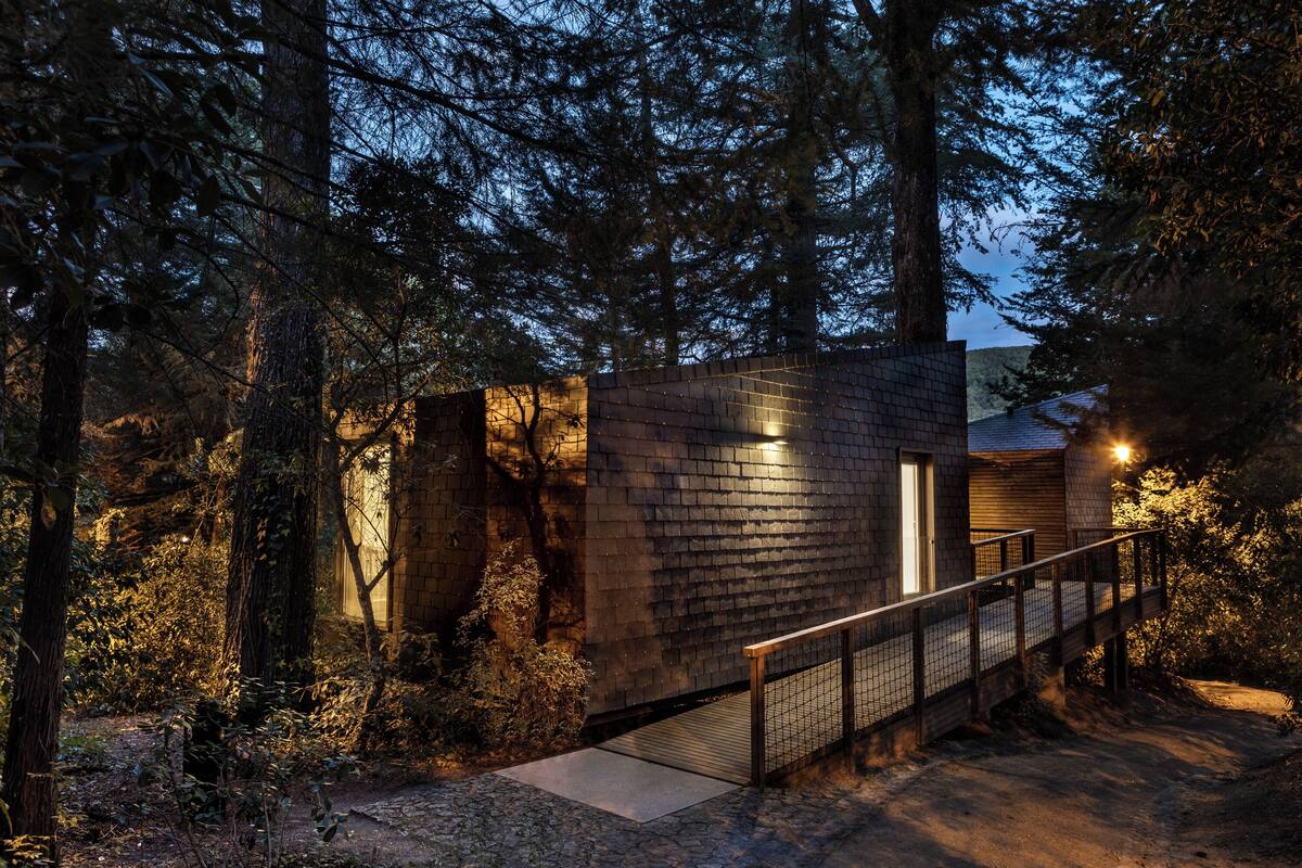 A modern building with a brick exterior, a wooden deck, and a metal railing.