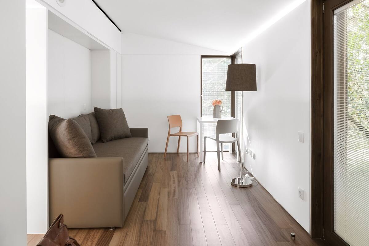 A modern, minimalist living room with a sofa, chairs, and a table.