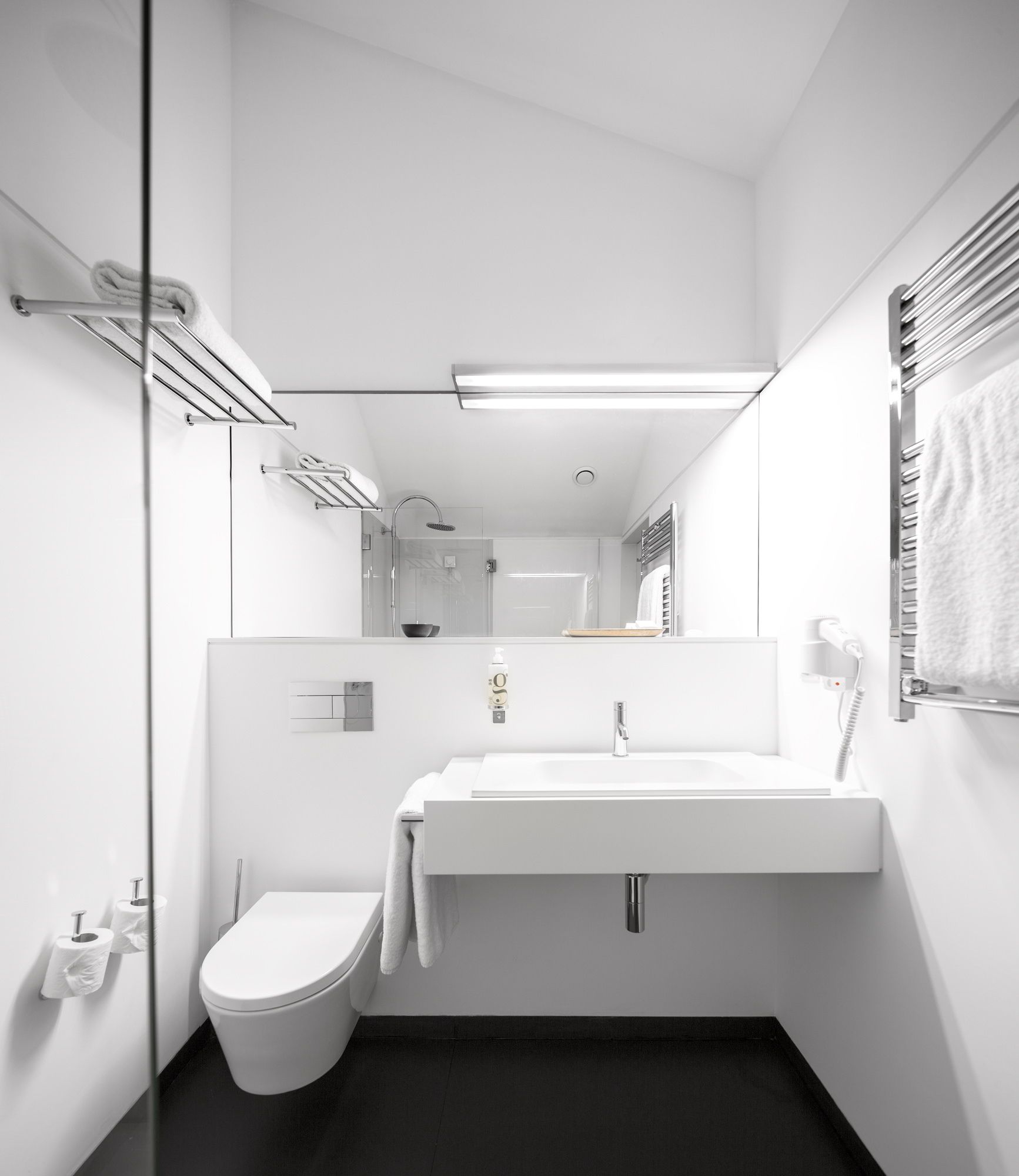 A modern bathroom with a white sink, toilet, and glass shower enclosure.