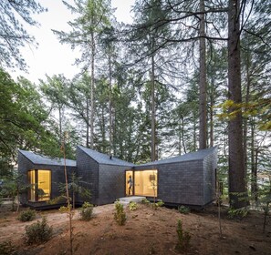 A modern cabin with two large glass doors, surrounded by a forest. - Pedras Salgadas Spa & Nature Park (Vila Pouca de Aguiar)
