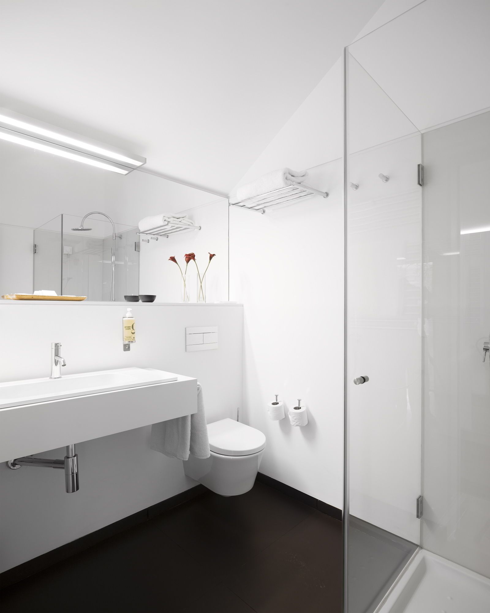Un bagno moderno con cabina doccia in vetro, lavandino bianco con specchio e un water.