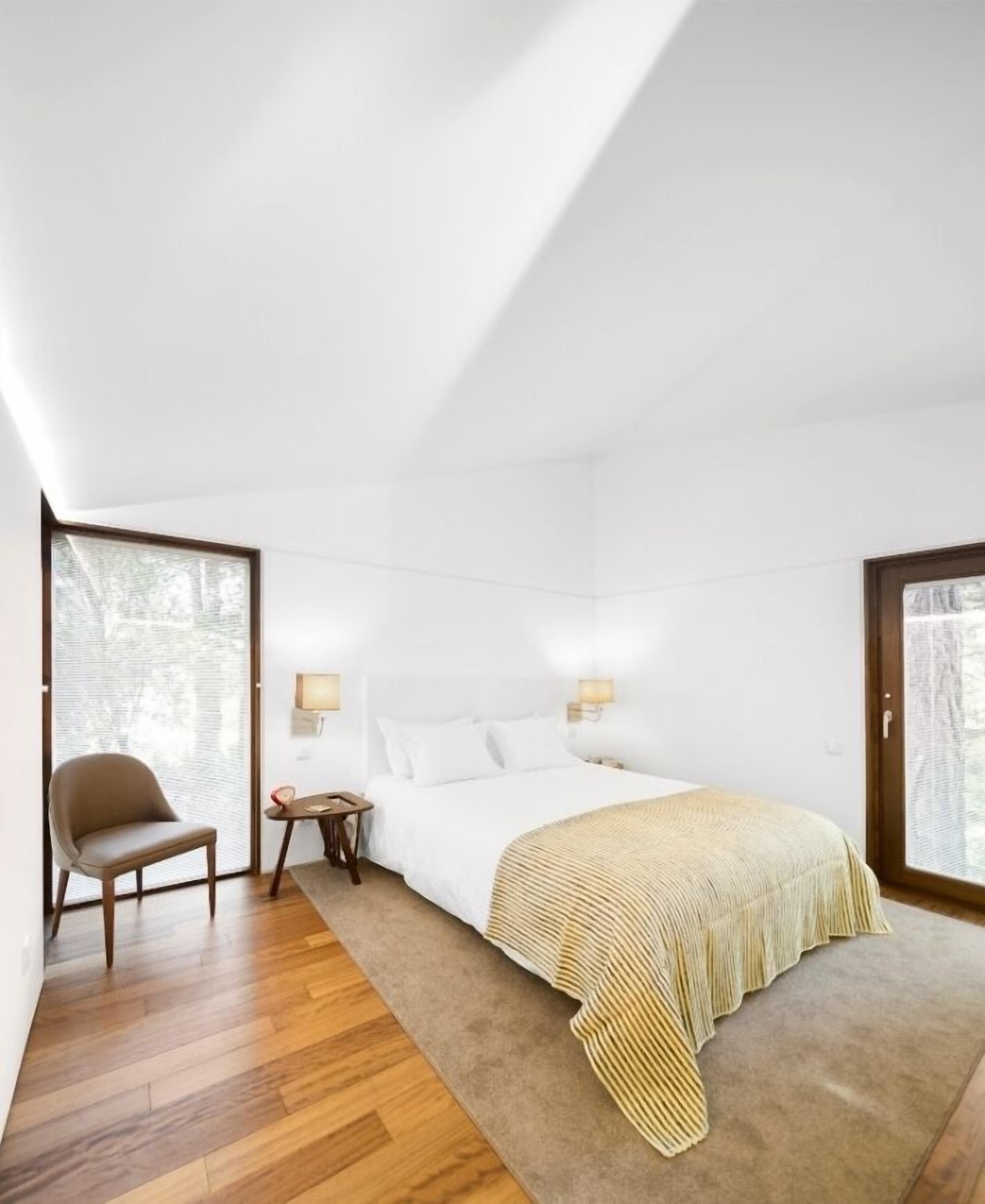 A modern bedroom with a large bed, a chair, and a small table.