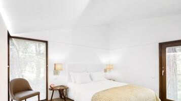 A modern bedroom with a large bed, a chair, and a small table.