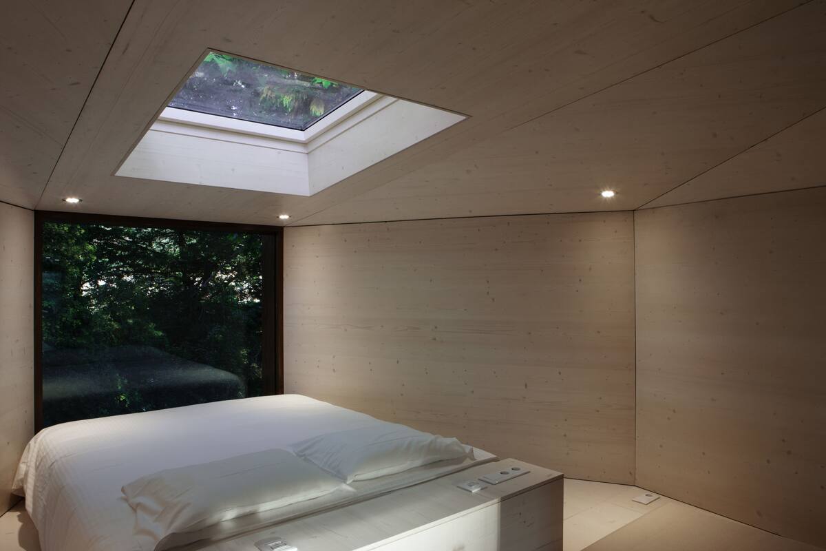 A modern bedroom with a skylight, a large window, and a minimalist design.