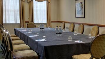 Un salón de conferencias con una larga mesa, sillas y botellas de agua.