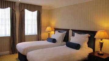 A hotel room with two beds, each with a pillow and a lamp on a bedside table.