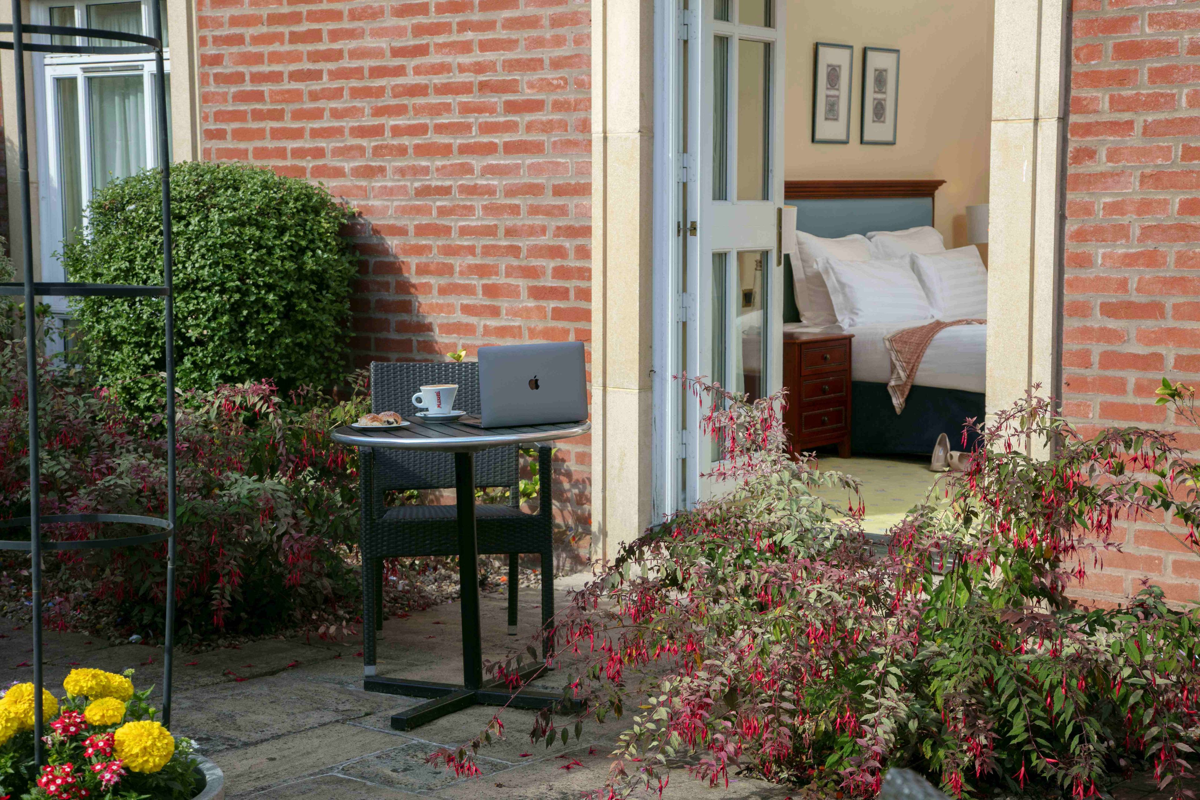 Ein Zimmer mit einem Bett, einem Laptop auf einem kleinen Tisch und einem Fenster mit Vorhängen.