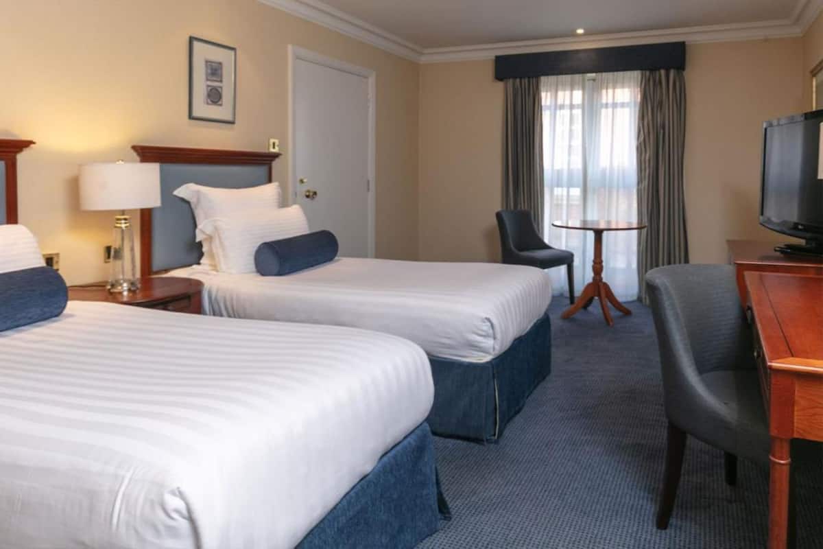 A hotel room with two beds, a TV, a desk, and a chair.