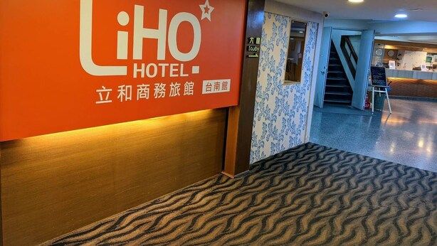 A hotel lobby with a prominent 'LiHO HOTEL' sign, a reception desk, and a staircase leading to another floor. - LIHO Hotel - Tainan (Tainan)