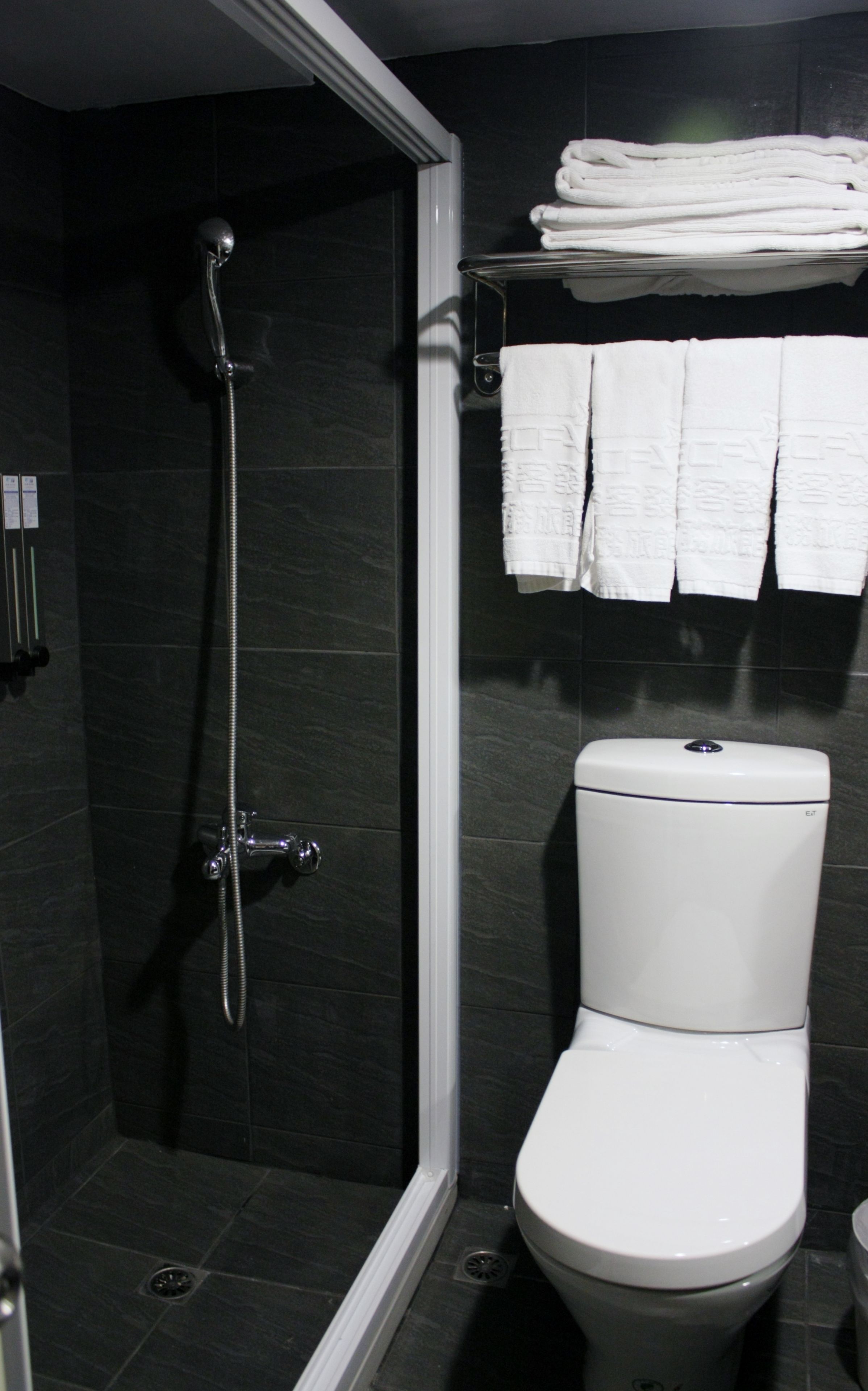 Une salle de bain équipée d’une douche, de toilettes et d’un porte-serviettes avec des serviettes pliées.