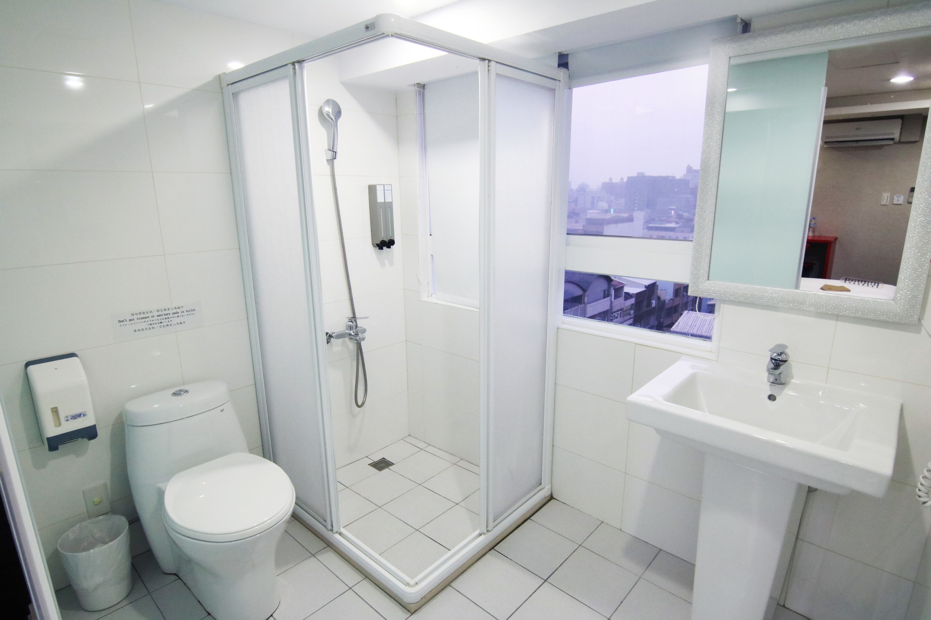 Un baño moderno con ducha de vidrio, un lavabo blanco y un inodoro.