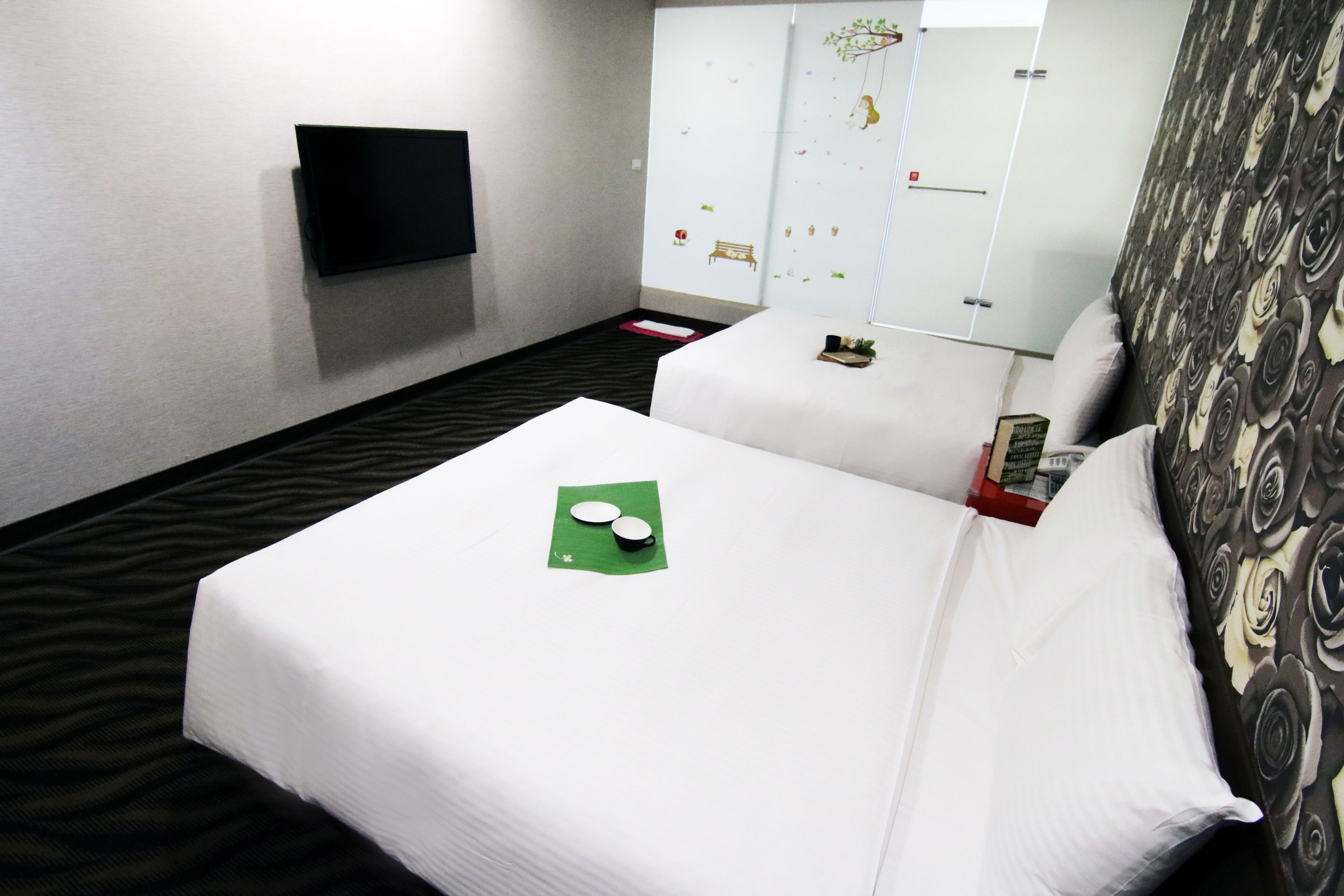 A hotel room with two beds, a flat-screen TV mounted on the wall, and a wardrobe with a mirror.