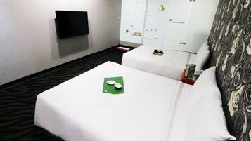 A hotel room with two beds, a flat-screen TV mounted on the wall, and a wardrobe with a mirror.
