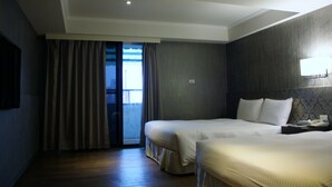 A hotel room with two beds, a large window with curtains, a flat-screen TV, and a bedside table with a lamp. - LIHO Hotel - Tainan (Tainan)