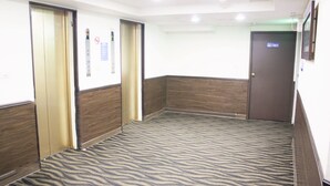 A hotel room with a zebra-patterned carpet, wooden paneling, a door labeled '1901', and an elevator with a control panel. - LIHO Hotel - Tainan (Tainan)