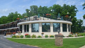 A two-story building with a curved balcony, large windows, and a stone base. - Amber's Inn & Suites (Wisconsin Dells)