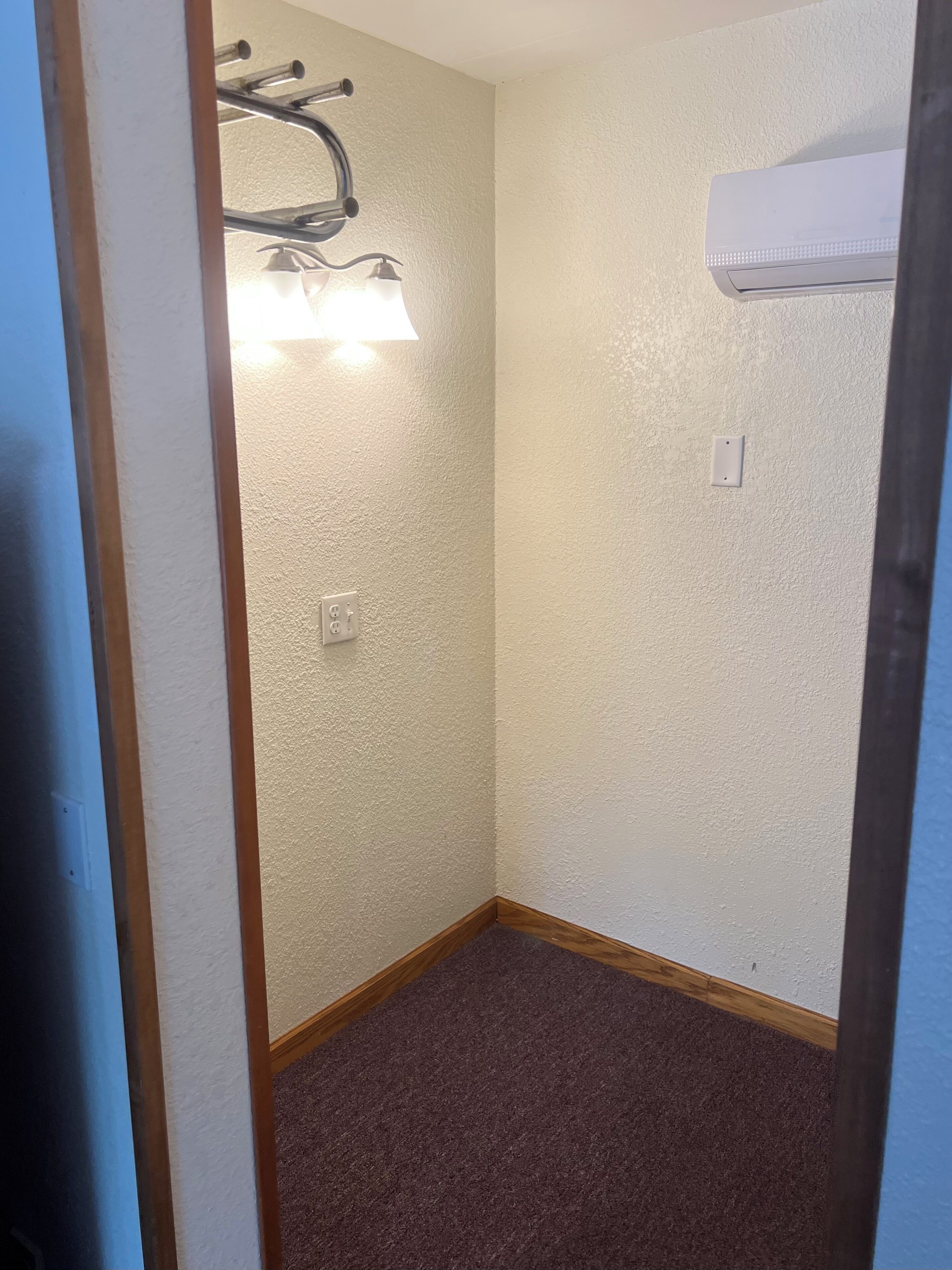 Habitació cantonera amb paret amb relleu, ventilador de sostre, aire condicionat i sòl amb moqueta.