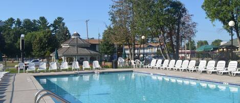 Una piscina al aire libre de temporada, sillones reclinables de piscina