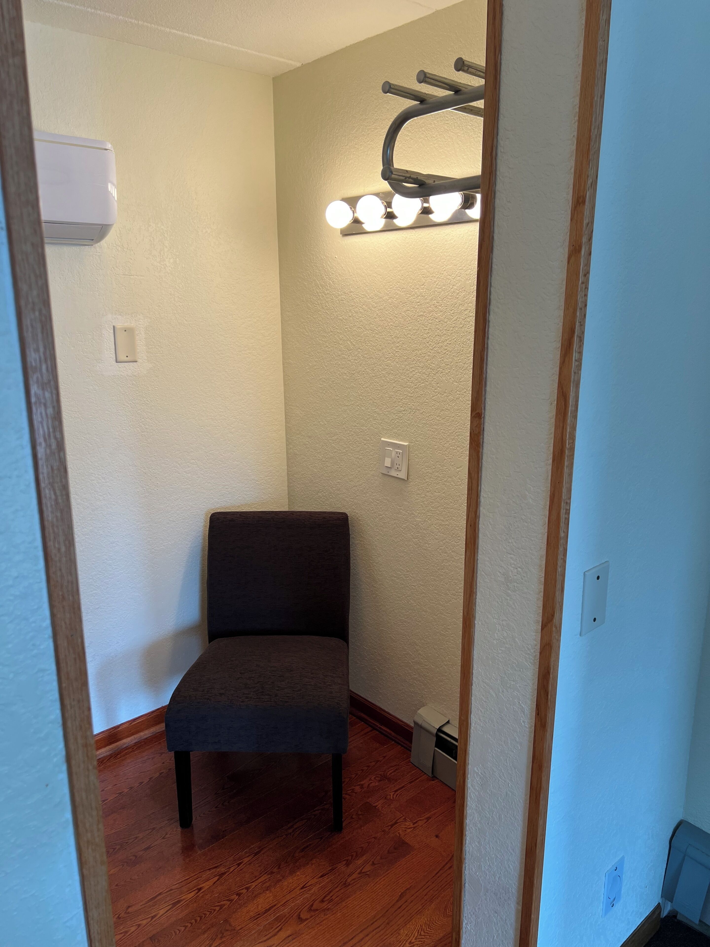 A room with a chair, a light fixture, and a wall-mounted air conditioner.
