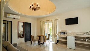 A modern living room with a dining area, a small kitchen, and a TV mounted on the wall. - Sahara Hotel (Playa del Carmen)