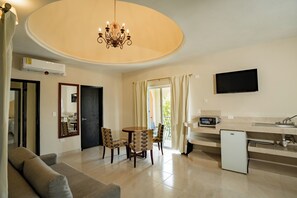Una sala de estar moderna con comedor, una pequeña cocina y un televisor montado en la pared.