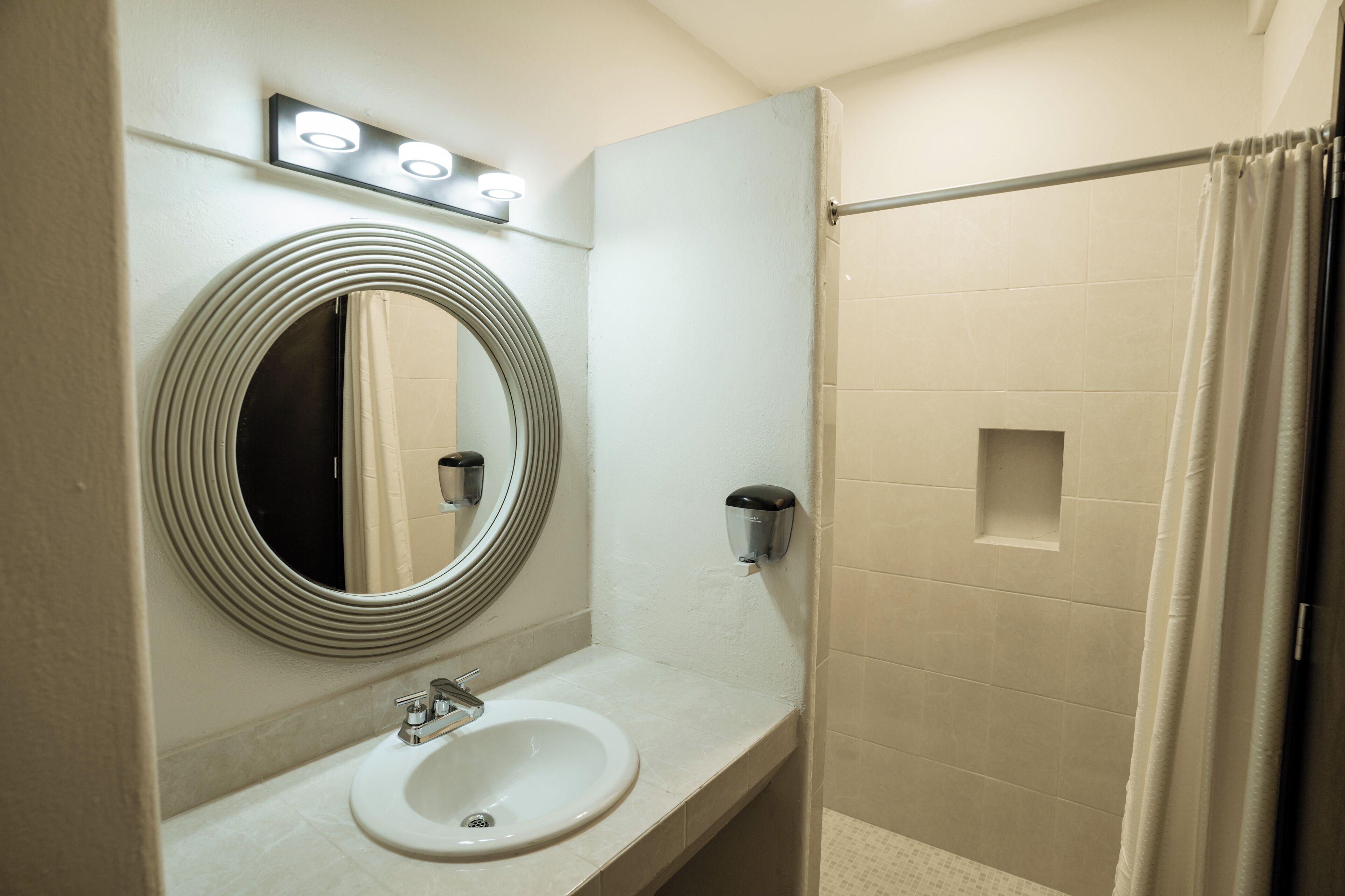 A bathroom with a sink, mirror, and shower curtain.