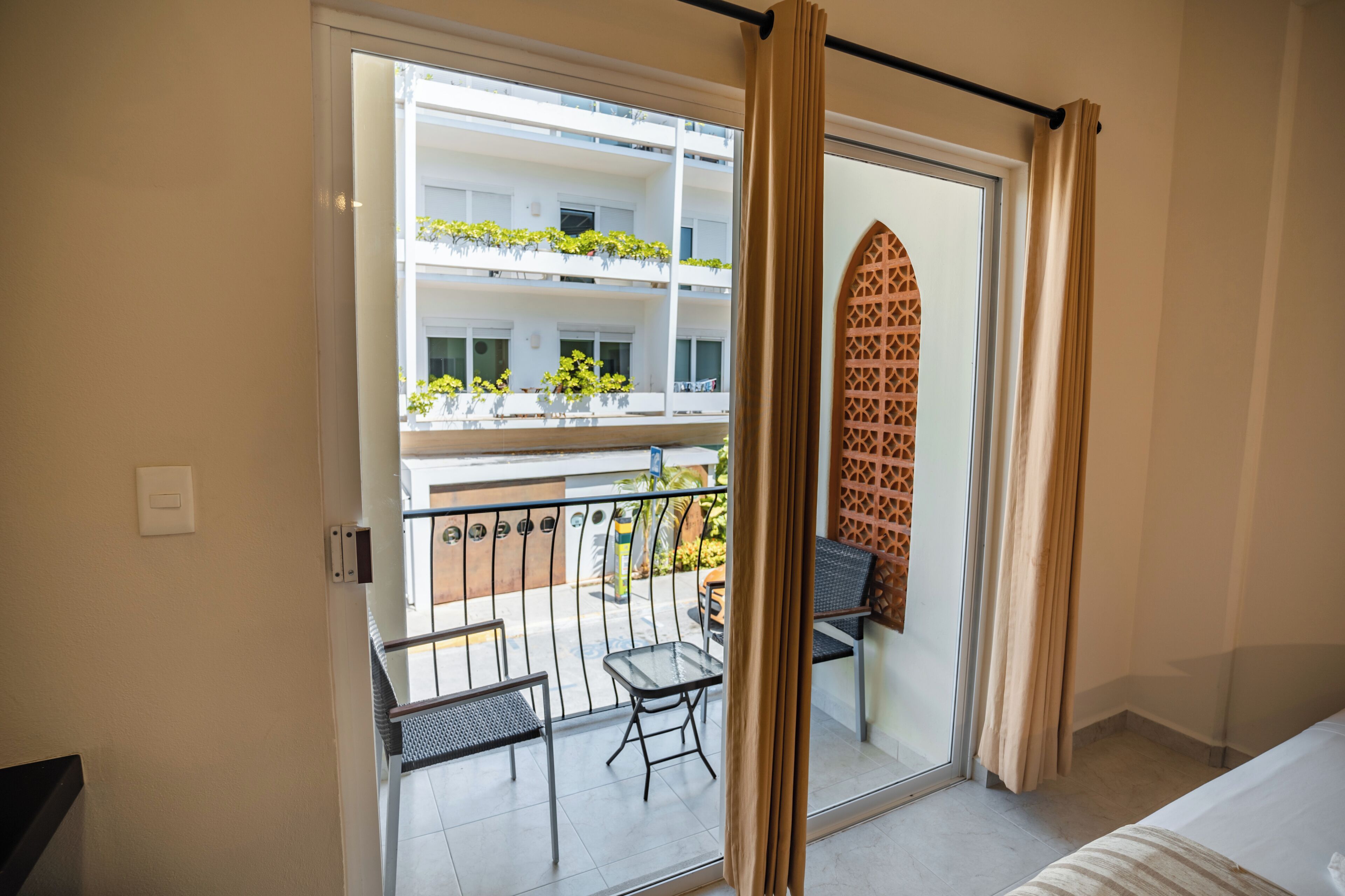 A hotel room with a balcony, a bed, and a view of a building with balconies.