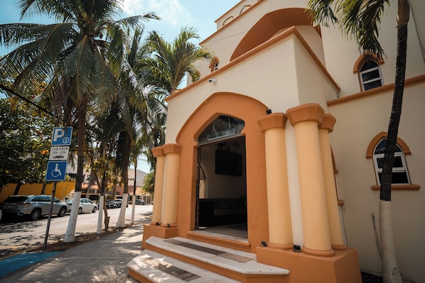 A building with a beige facade, a parking sign, and palm trees. - Sahara Hotel (Playa del Carmen)