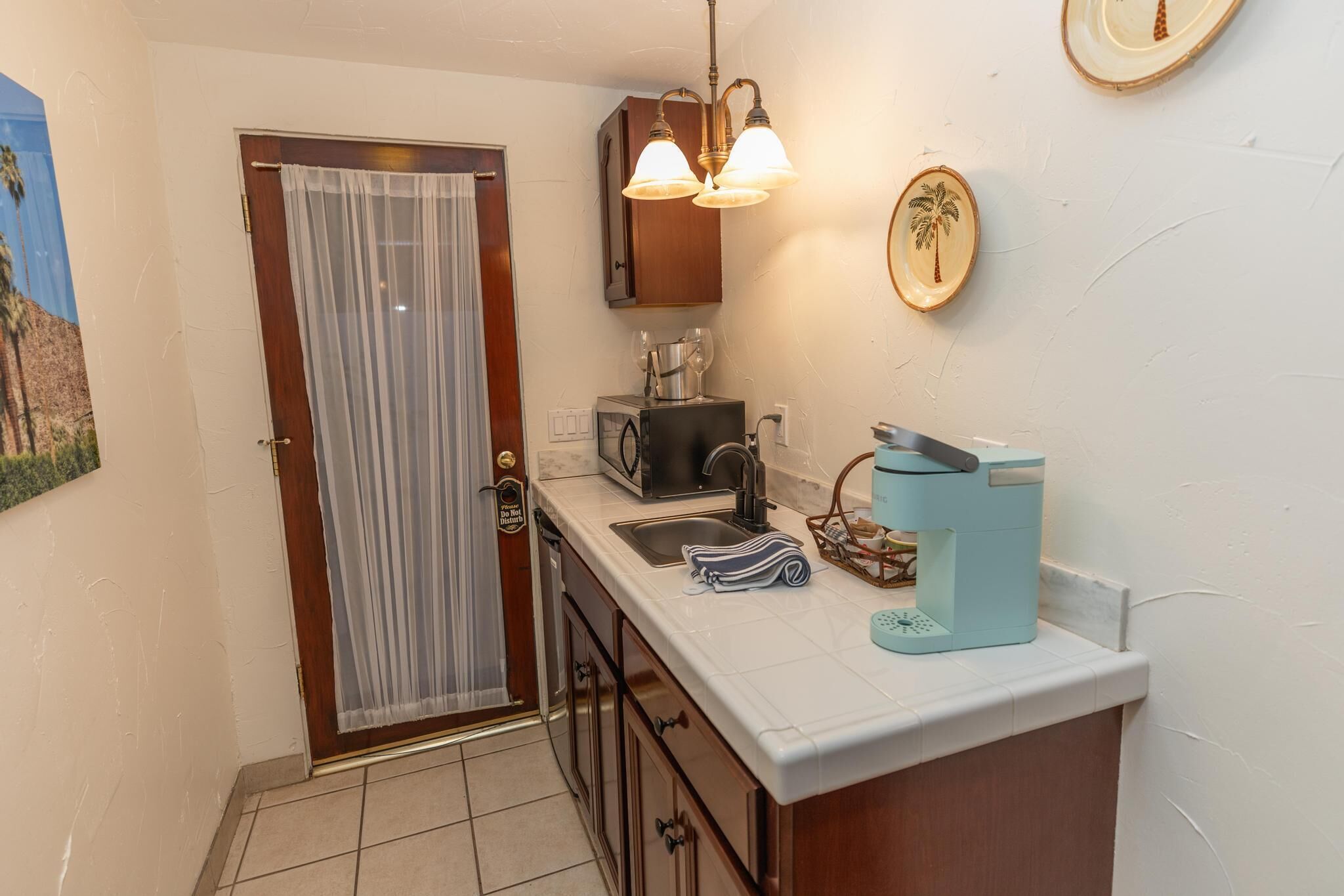 Una cocina compacta equipada con refrigerador, microondas, cafetera y pileta.