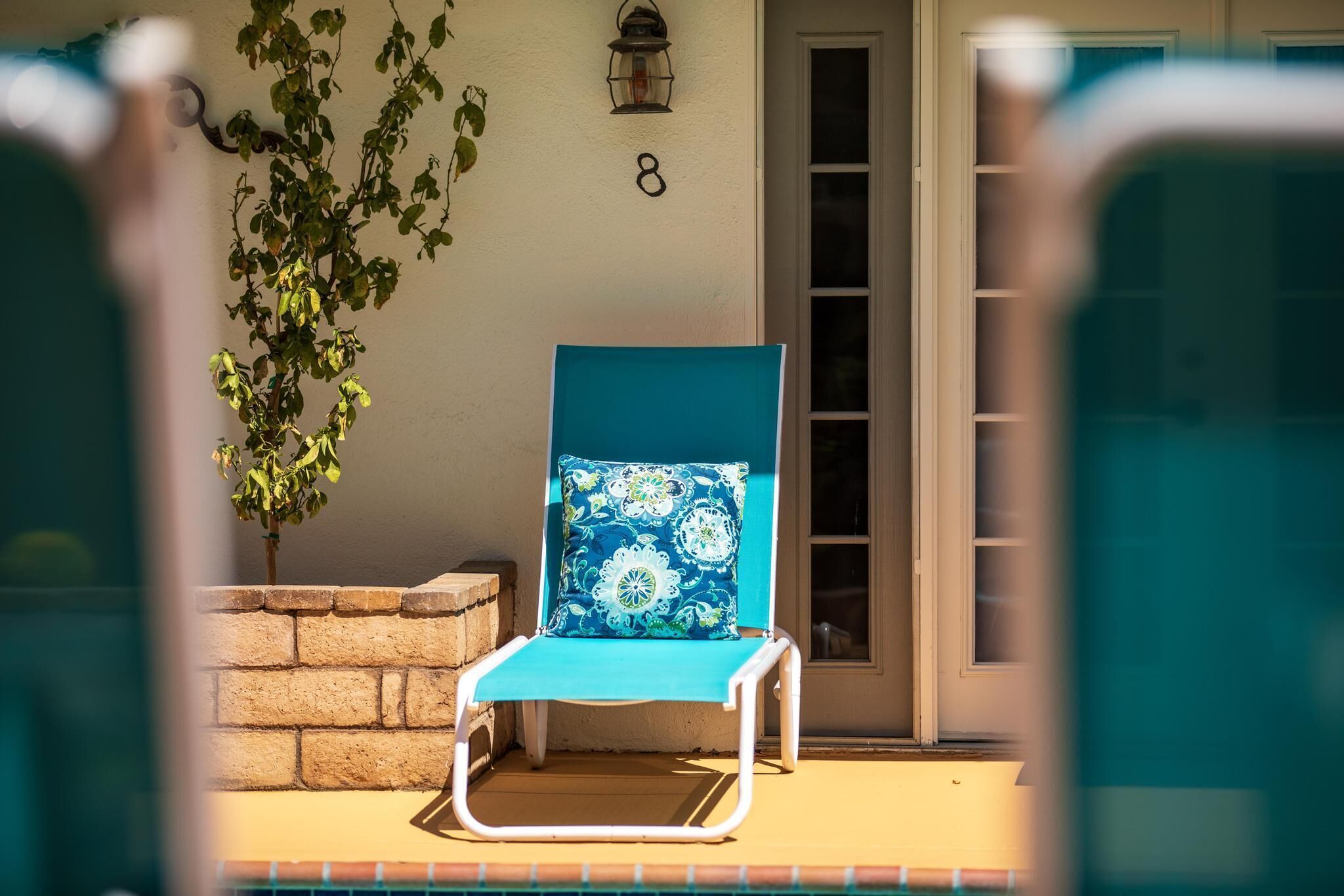 A sunlit outdoor seating area with a blue chair and a potted plant.