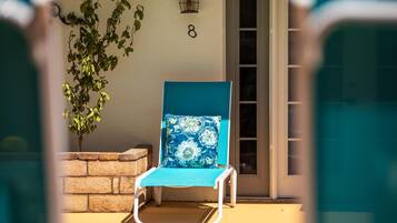 A sunlit outdoor seating area with a blue chair and a potted plant.