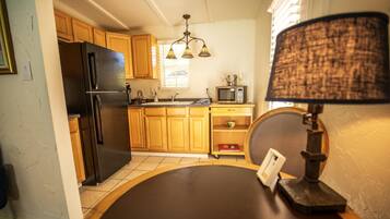 Una cocina con armarios de madera, un refrigerador negro, un microondas y un candelabro.