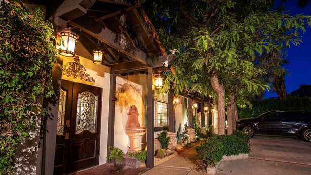 A building with a traditional architectural style, featuring a stone facade, ornate door, and a pathway leading to the entrance. - Old Ranch Inn - Adults Only  (Palm Springs)