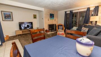 A living room with a television, a fireplace, a sofa, and a dining table.