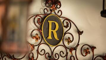A decorative metal sign with a large 'R' in the center, surrounded by ornate metalwork.